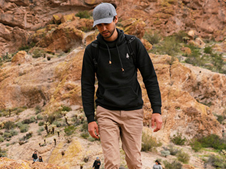 A man wearing tentree apparel hiking in an arid climate.